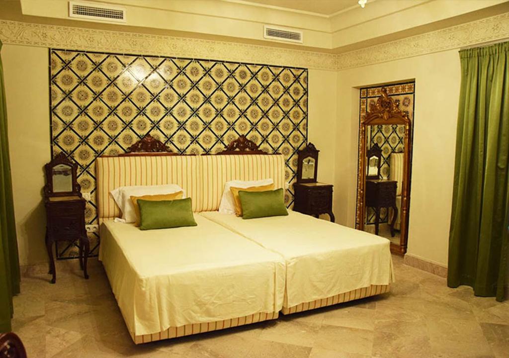 a bedroom with a large white bed with green pillows at Dar ALOUINI in Kairouan