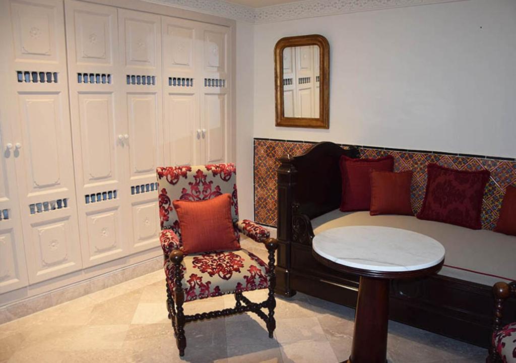 a bedroom with a bed and a chair and a table at Dar ALOUINI in Kairouan