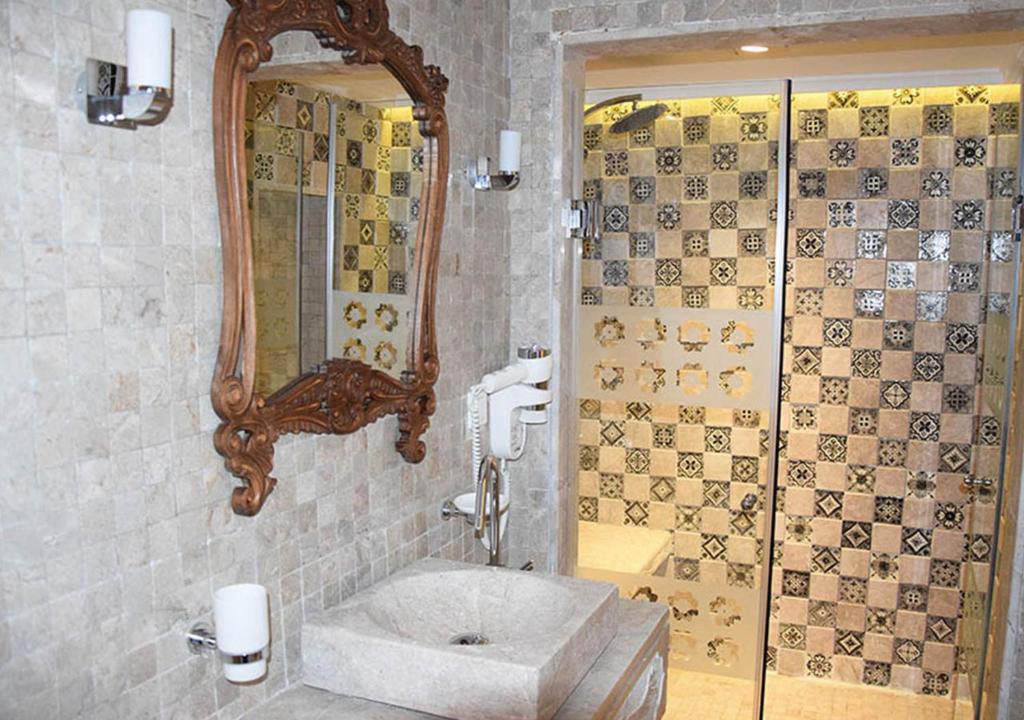 a bathroom with a shower and a sink and a mirror at Dar ALOUINI in Kairouan