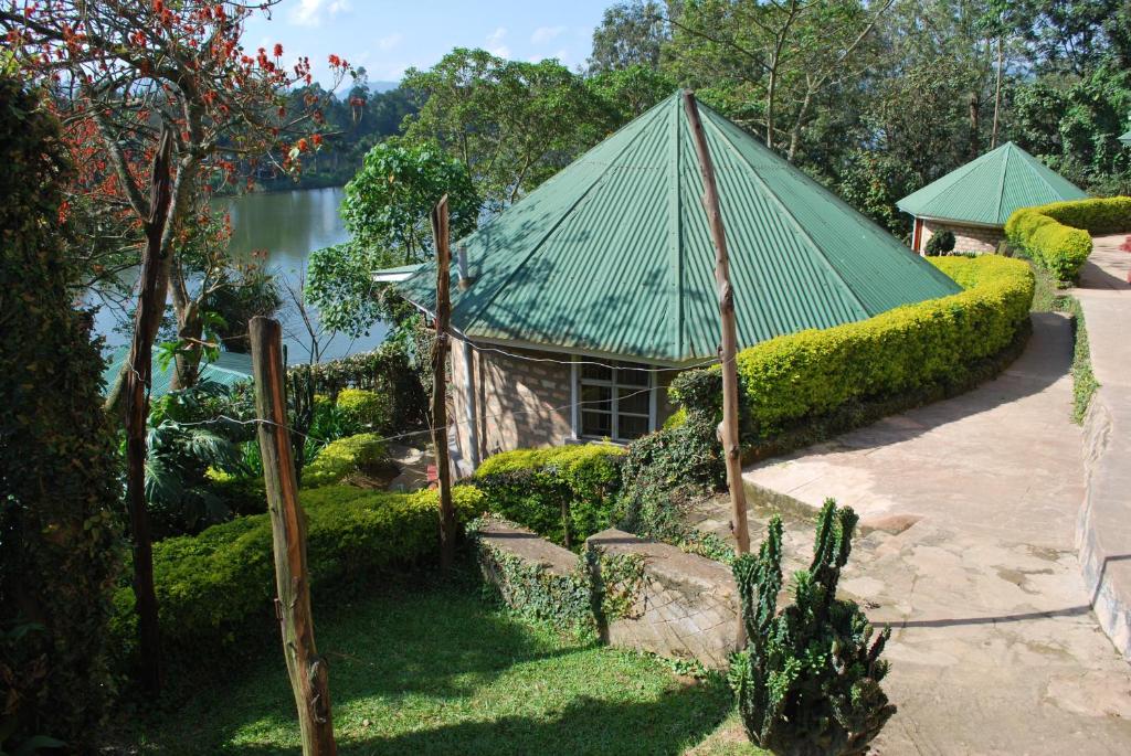 a building with a green roof next to a lake at Crater Bay Cottages in Kabale