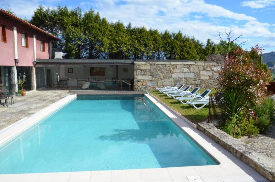 uma piscina com cadeiras e uma casa em Moradia Integrada T0 em Hotel Rural 4.* em Braga