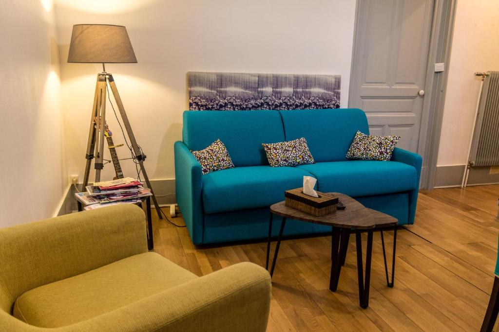 a living room with a blue couch and two chairs at La ptite chouette in Dijon
