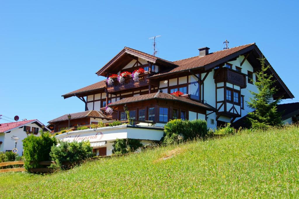 a house on the side of a hill with flowers at Gästehaus Alpenruh in Fischen