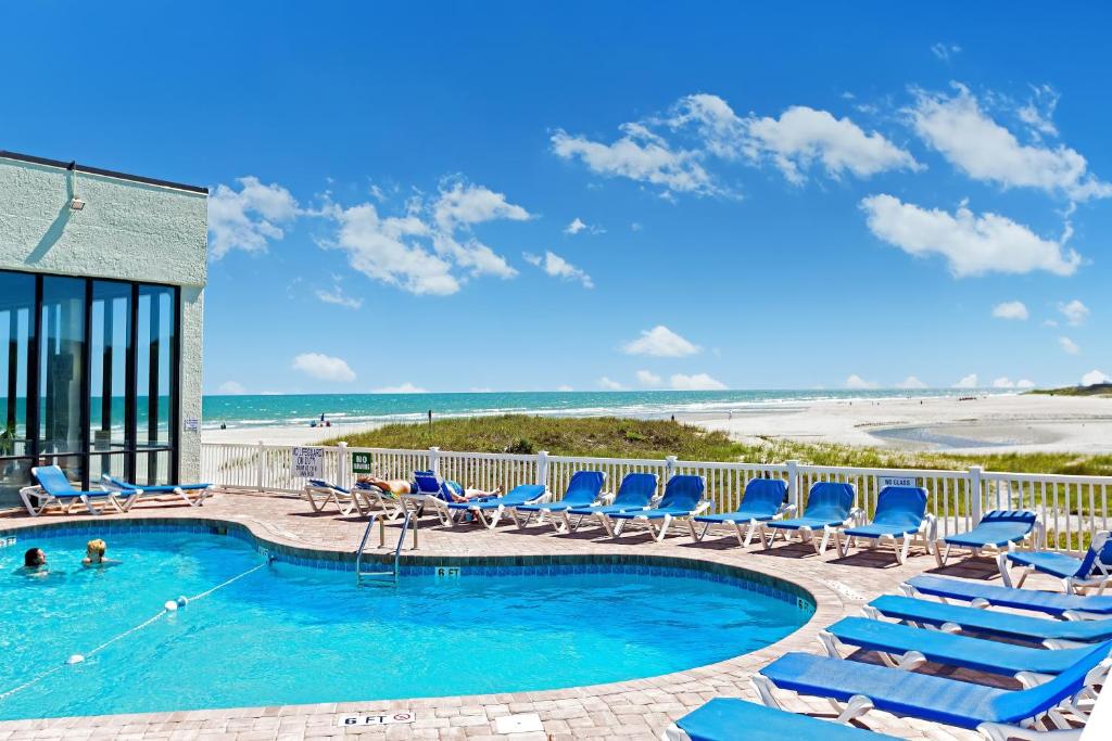 a swimming pool with lounge chairs and the beach at Sands Beach Club Resort in Myrtle Beach
