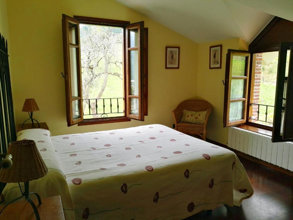 een slaapkamer met een groot bed en 2 ramen bij Finca Artienza in Ramales de la Victoria