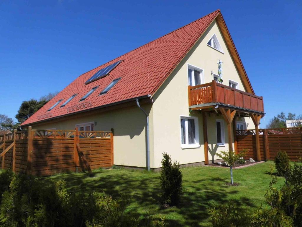 a house with a red roof and a wooden fence at Ferienzimmer Quint nahe Kap Arkona in Altenkirchen