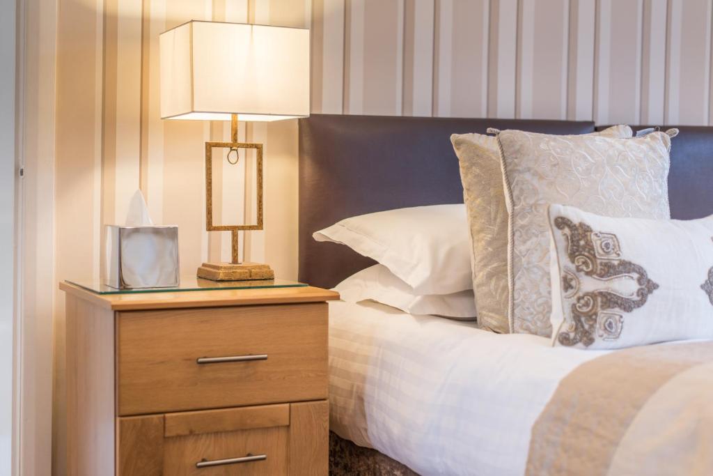 a bed with a night stand with a lamp on it at Grovefield Manor in Poole