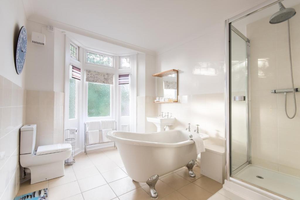 a white bathroom with a tub and a sink at Grovefield Manor in Poole