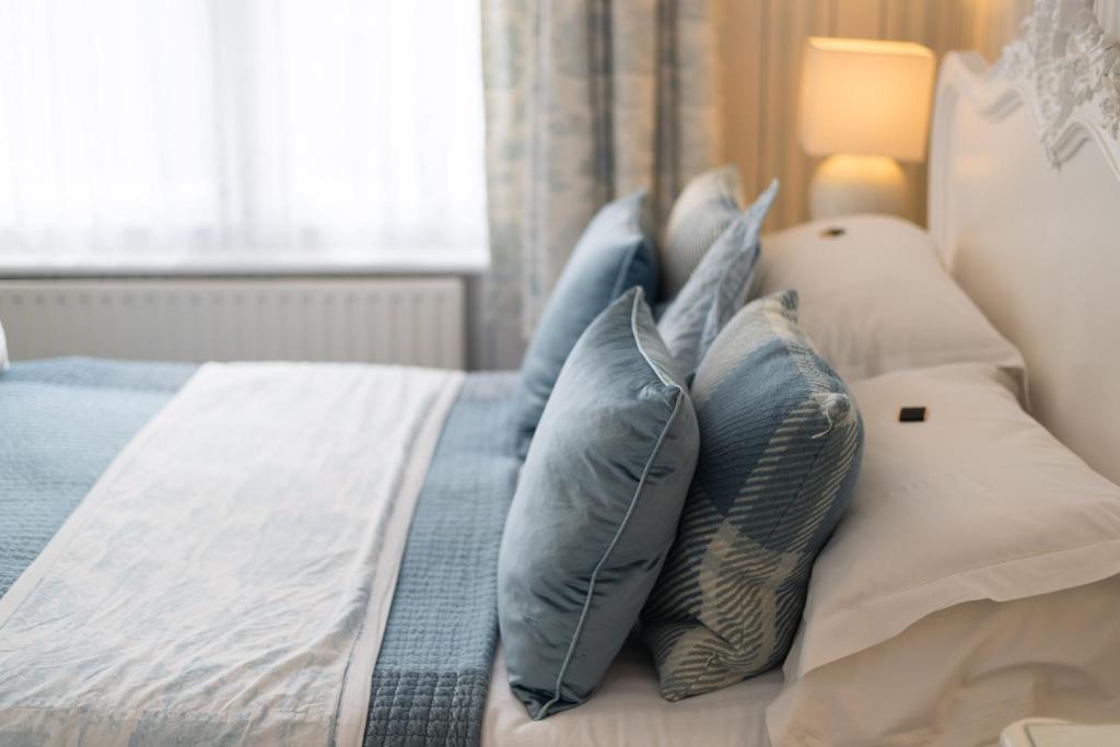 a bed with blue and white pillows on it at Grovefield Manor in Poole