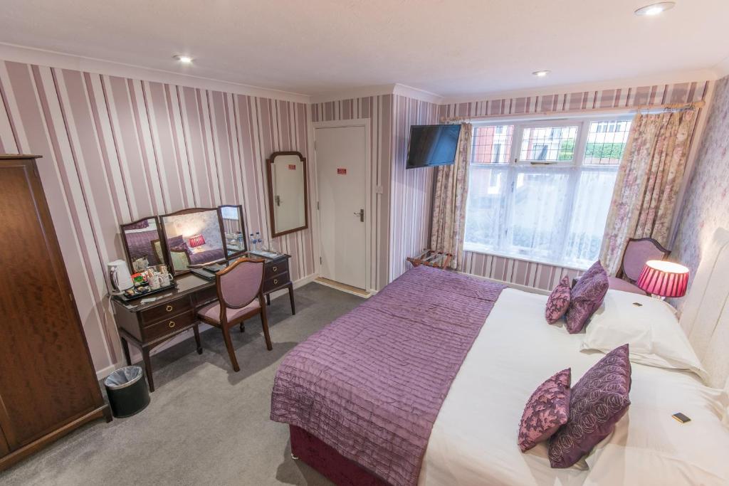 a bedroom with a bed and a desk and a mirror at Grovefield Manor in Poole