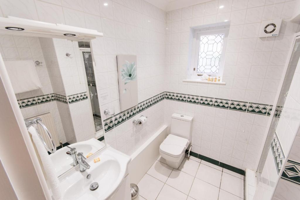 a white bathroom with a toilet and a sink at Grovefield Manor in Poole