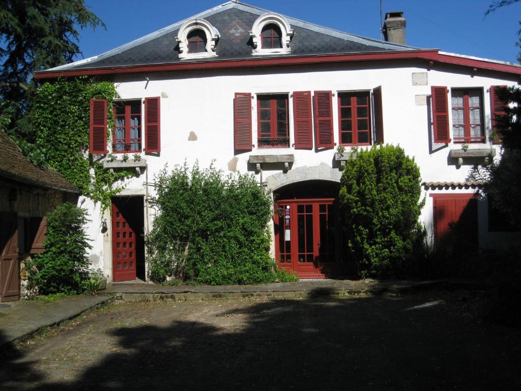 a white house with red shutters and red doors at Chambres d'Hôtes Closerie du Guilhat in Salies-de-Béarn