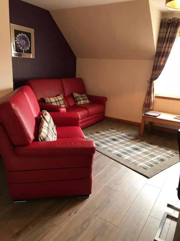 a living room with a red couch and a window at Cairngorm Mountain View in Aviemore