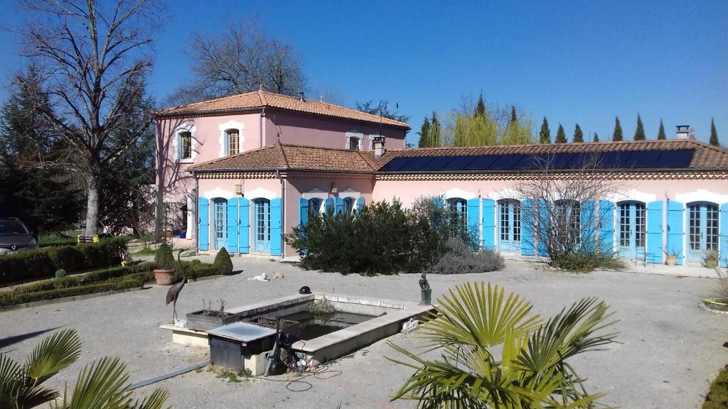 une grande maison avec des portes bleues et une cour dans l'établissement La table de Pierre, à Lussas-et-Nontronneau