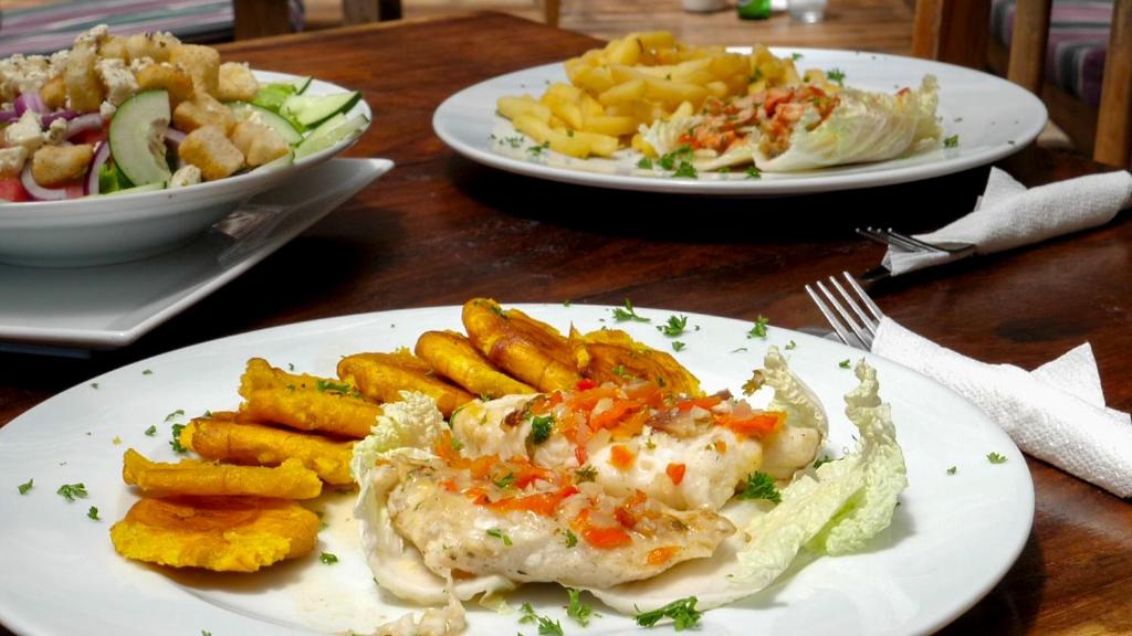 a table with two plates of food and fries at Hotel Playa Reina in Llano de Mariato