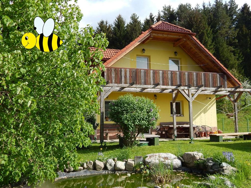 een geel huis met een bijenteken ervoor bij Sunny Holiday House B&B in Ljubno