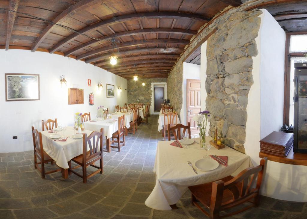restauracja ze stołami i krzesłami oraz kamienną ścianą w obiekcie Hotel Rural Bentor w mieście Los Realejos