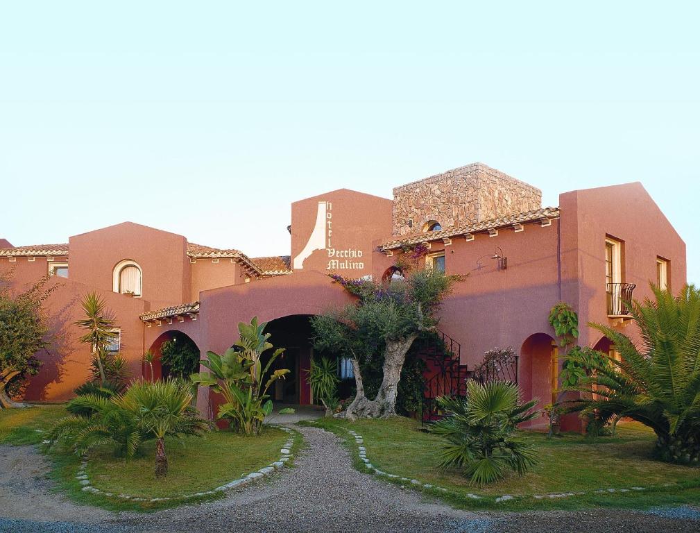 ein Haus mit Palmen davor in der Unterkunft Hotel Il Vecchio Mulino in Àrbatax