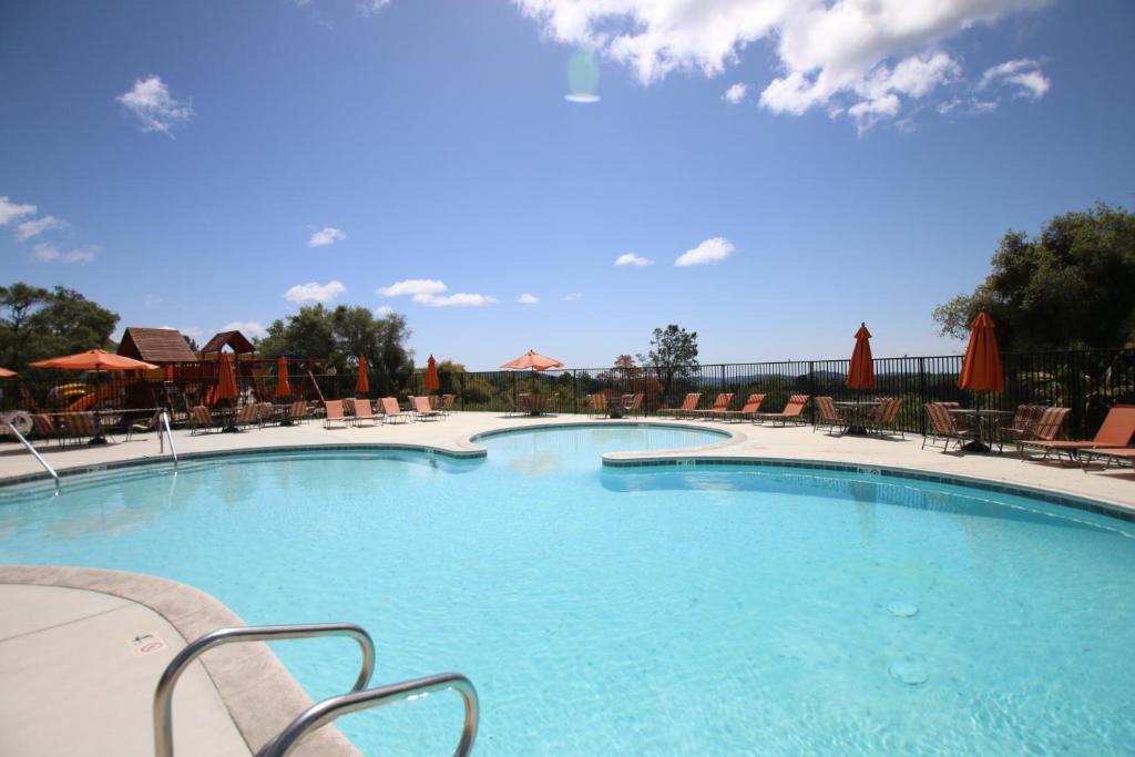 a large swimming pool with chairs and umbrellas at Yosemite RV Resort in Coarsegold