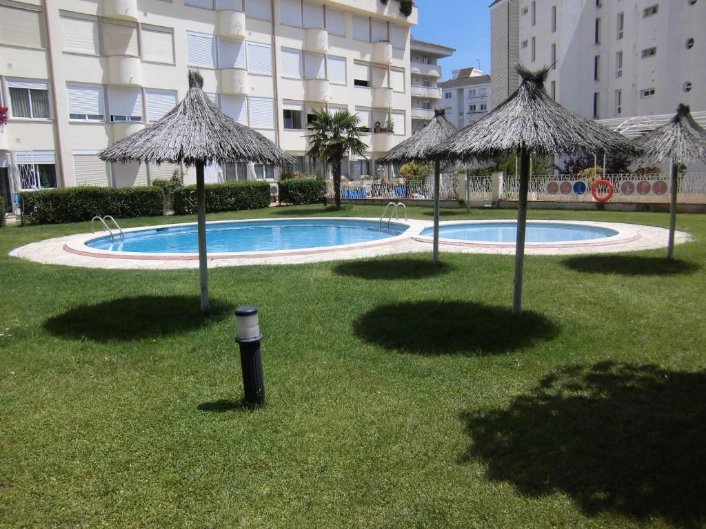a swimming pool with umbrellas in the grass next to a building at Majestic in Lloret de Mar