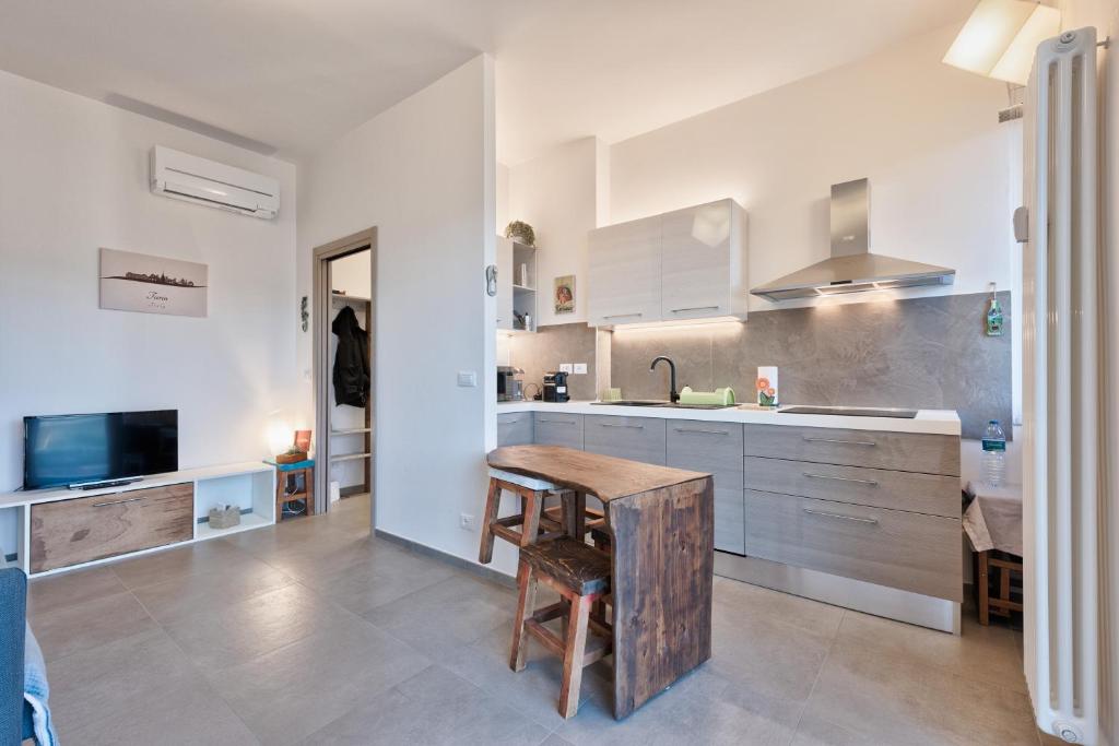 uma cozinha com armários brancos e uma mesa de madeira em Attico Valentino Cellini em Turim