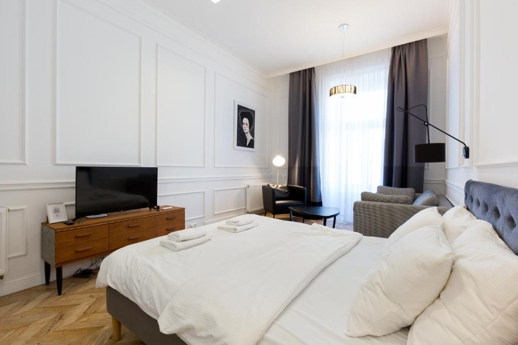 a bedroom with a white bed and a living room at The Oktogon Executive Apartment in Budapest