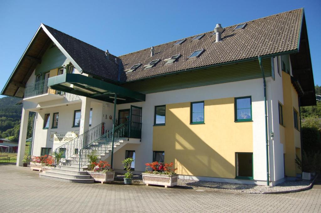 een geel en wit gebouw met een dak bij Gasthaus Pension Zum lustigen Steirer in Bruck an der Mur
