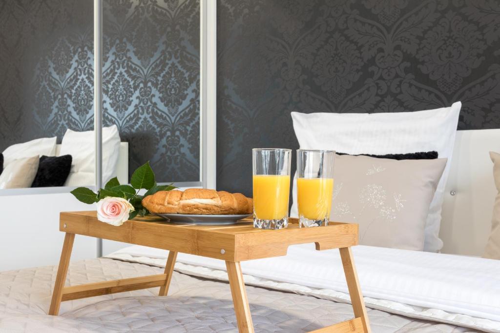 een dienblad met twee glazen sinaasappelsap en brood op een bed bij Angel Apartament in Krakau