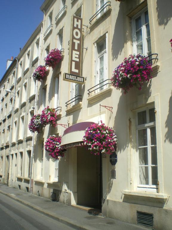 un bâtiment avec des paniers de fleurs sur son côté dans l'établissement Cit'Hotel Hôtel Beauséjour, à Cherbourg en Cotentin