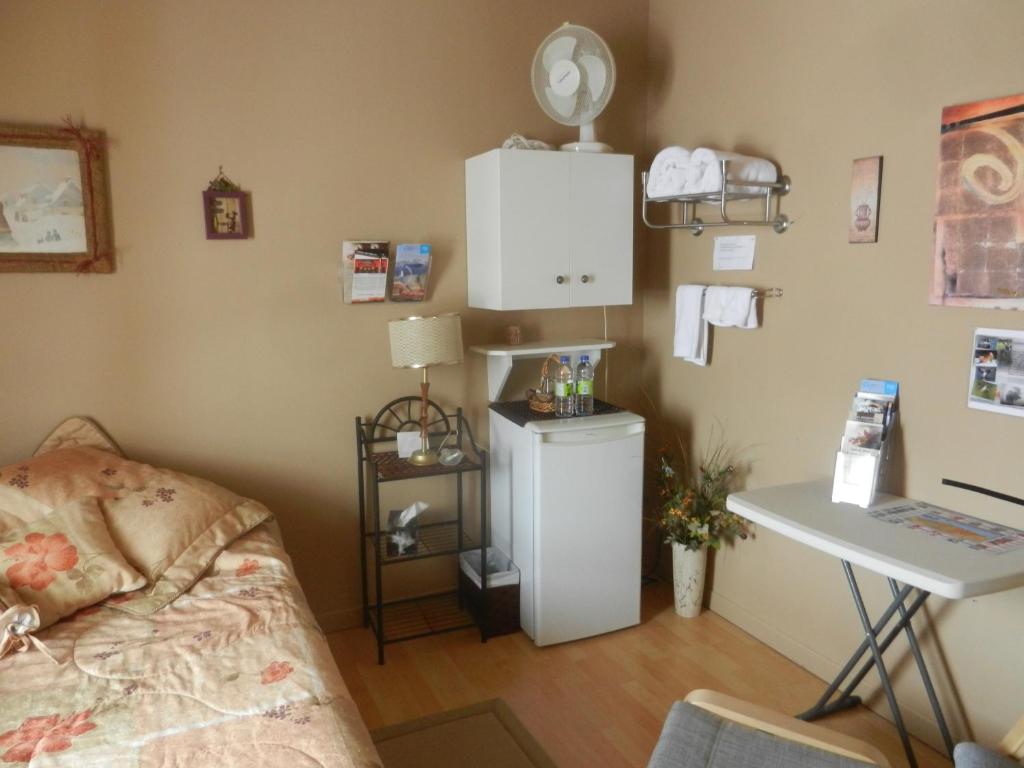 a room with a bed and a table and a desk at Gite La Ptite Falaise hébergement touristique in Sainte-Anne-des-Monts
