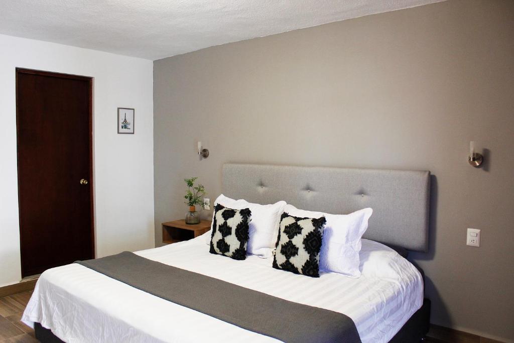 1 dormitorio con 1 cama grande con almohadas blancas y negras en Suites ciento 37, en León