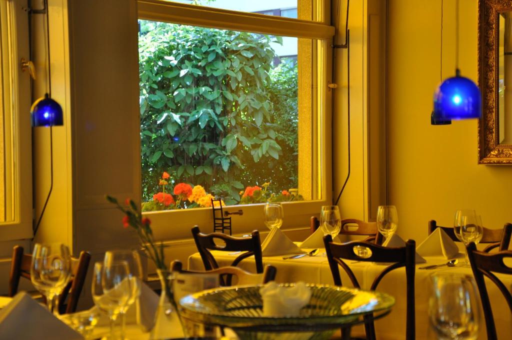 ein Esszimmer mit Tischen, Stühlen und einem Fenster in der Unterkunft Hotel Landhus in Zürich
