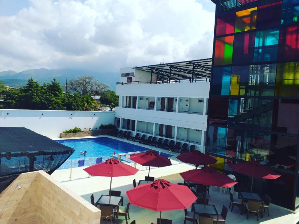 梅爾加的住宿－Hotel Karmel，一座游泳池,旁边是一座建筑,上面有红伞