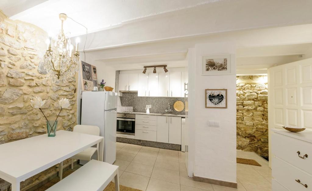 Bravissimo Old Side Girona Two, centre Barri Vell في جيرونا: مطبخ بطاولة بيضاء وجدار حجري