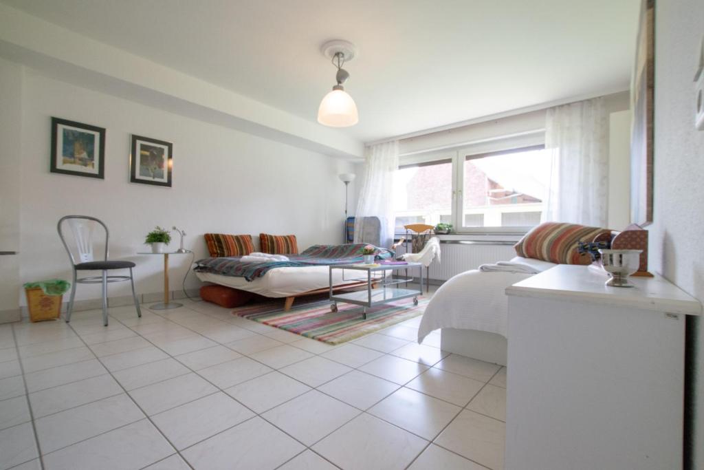 ein weißes Wohnzimmer mit einem Bett und einem Tisch in der Unterkunft Big 1 Room Apartment - 15 Min Messe DUS in Meerbusch