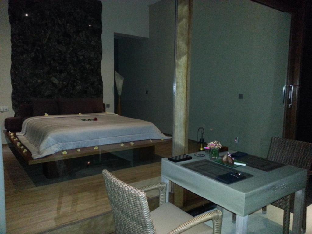 a bedroom with a bed and a table and chairs at The Puncak Lombok in Senggigi