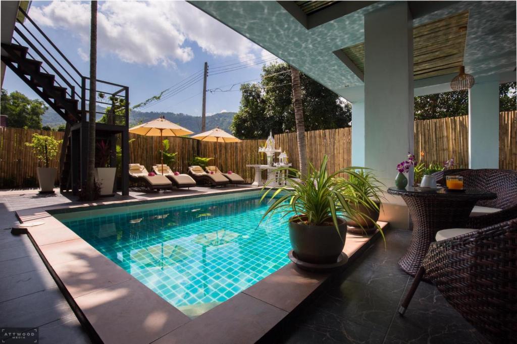a swimming pool in a backyard with chairs and a table at Samui Star Guesthouse in Chaweng