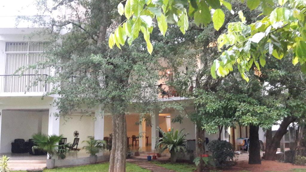 una casa blanca con árboles delante de ella en Sudunelum Holiday Resort en Anuradhapura