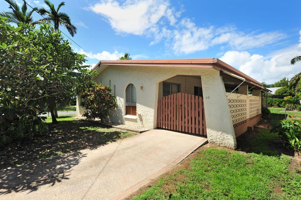 a small white house with a gate and a driveway at Seascape Holidays - 53 Reef Street in Port Douglas