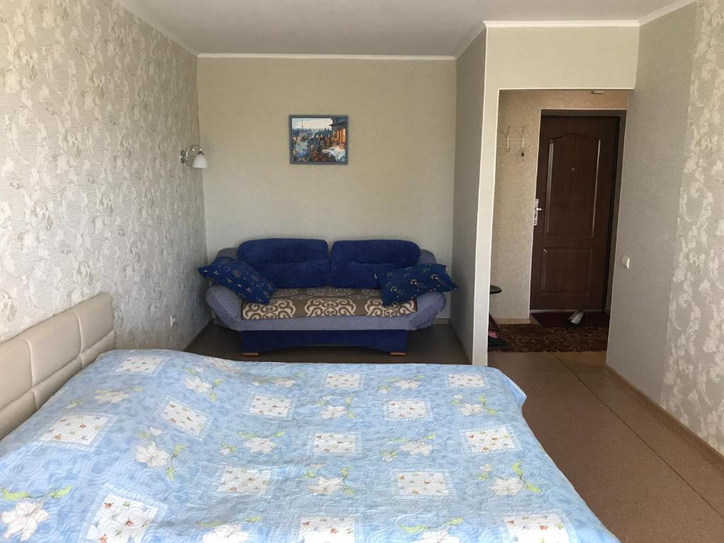 a bedroom with a blue bed and a couch at Apartment on Amurskiy Bulvar 62 in Khabarovsk