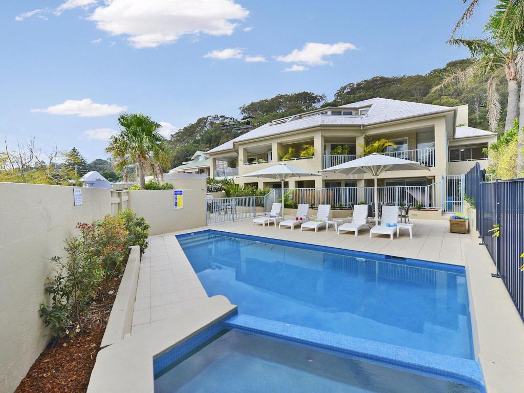 a house with a swimming pool in front of a house at Boathouse at Iluka Resort Apartments in Palm Beach