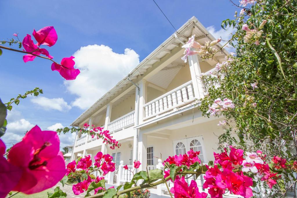 una casa blanca con flores rosas delante en Rosewood Apartment Hotel, en Arnos Vale