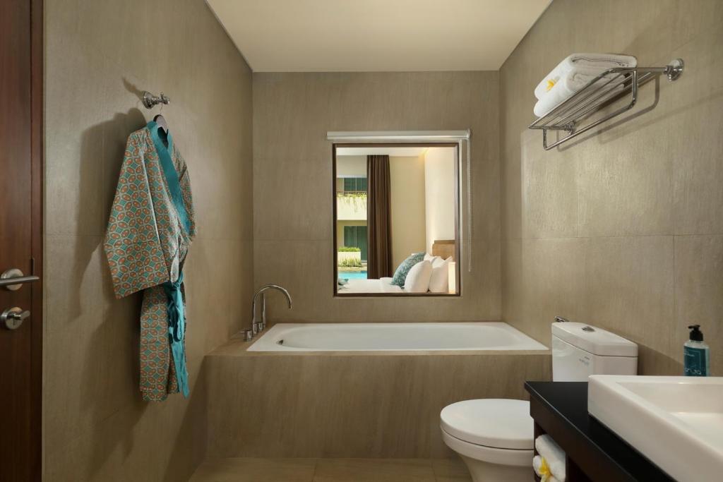 a bathroom with a tub and a toilet and a sink at Anja Jimbaran in Jimbaran