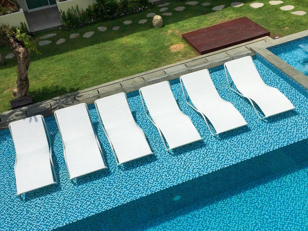 a row of white chairs sitting on top of a swimming pool at Anja Jimbaran in Jimbaran