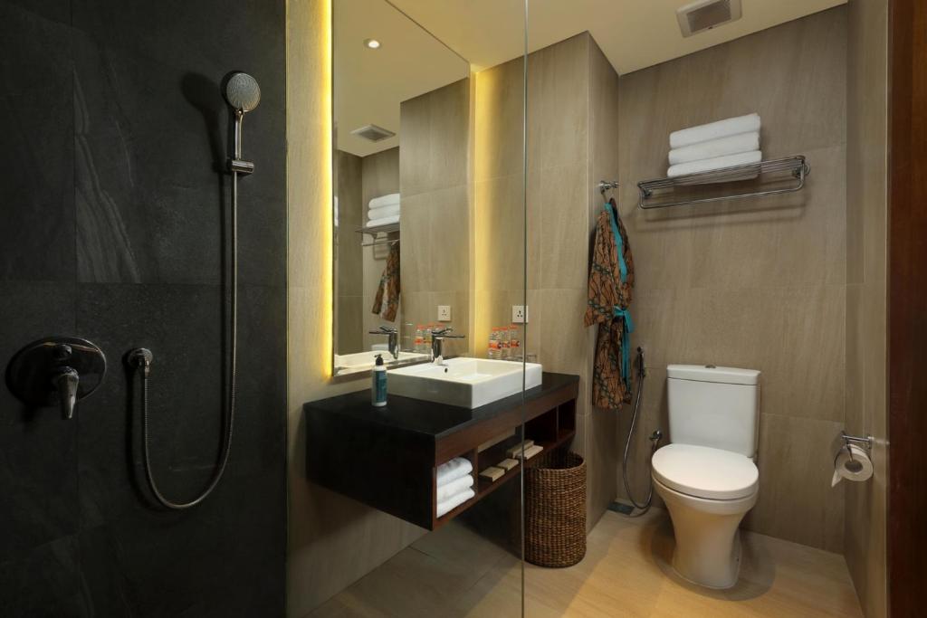 a bathroom with a toilet and a sink and a mirror at Anja Jimbaran in Jimbaran