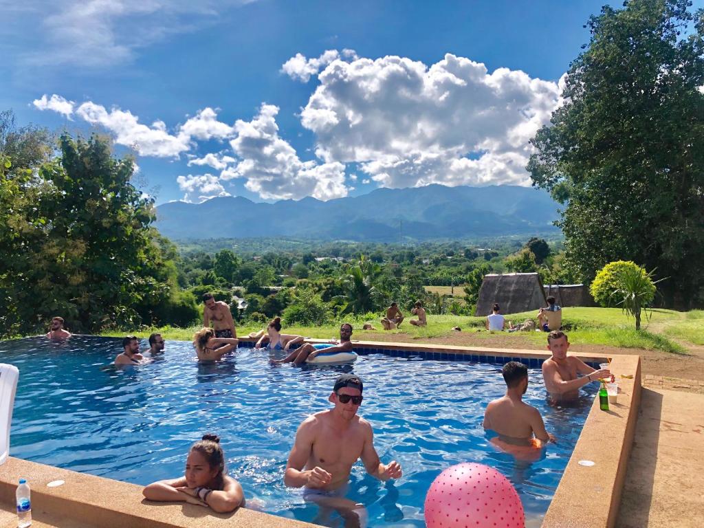 a group of people sitting in a swimming pool at Pai circus hostel in Pai