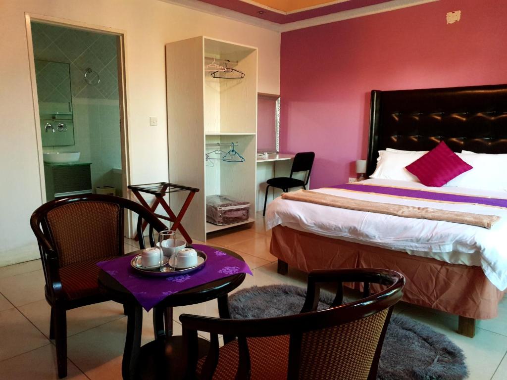 sypialnia z łóżkiem, stołem i krzesłami w obiekcie Mathlyn Guest House w mieście Francistown