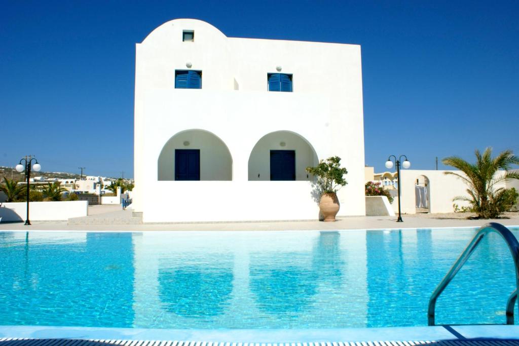 a swimming pool in front of a white building at Blue Bay Villas in Kamari