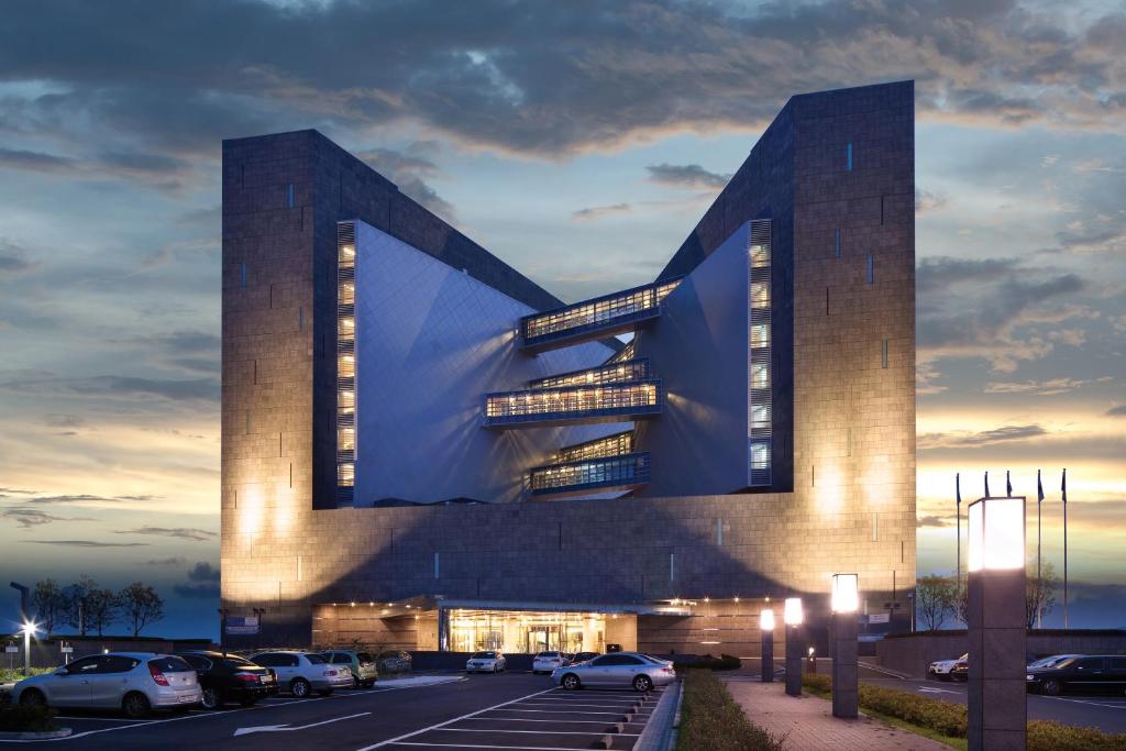 a building with cars parked in a parking lot at Hidden Bay Hotel in Yeosu