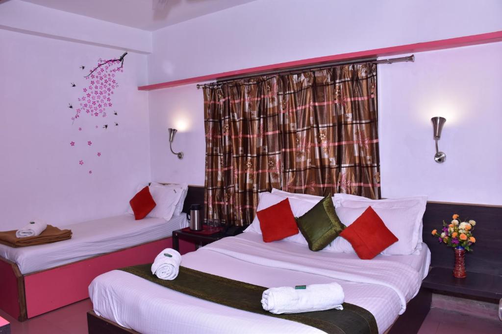 a hotel room with two beds and a window at Rahi Hotel in Mahabaleshwar